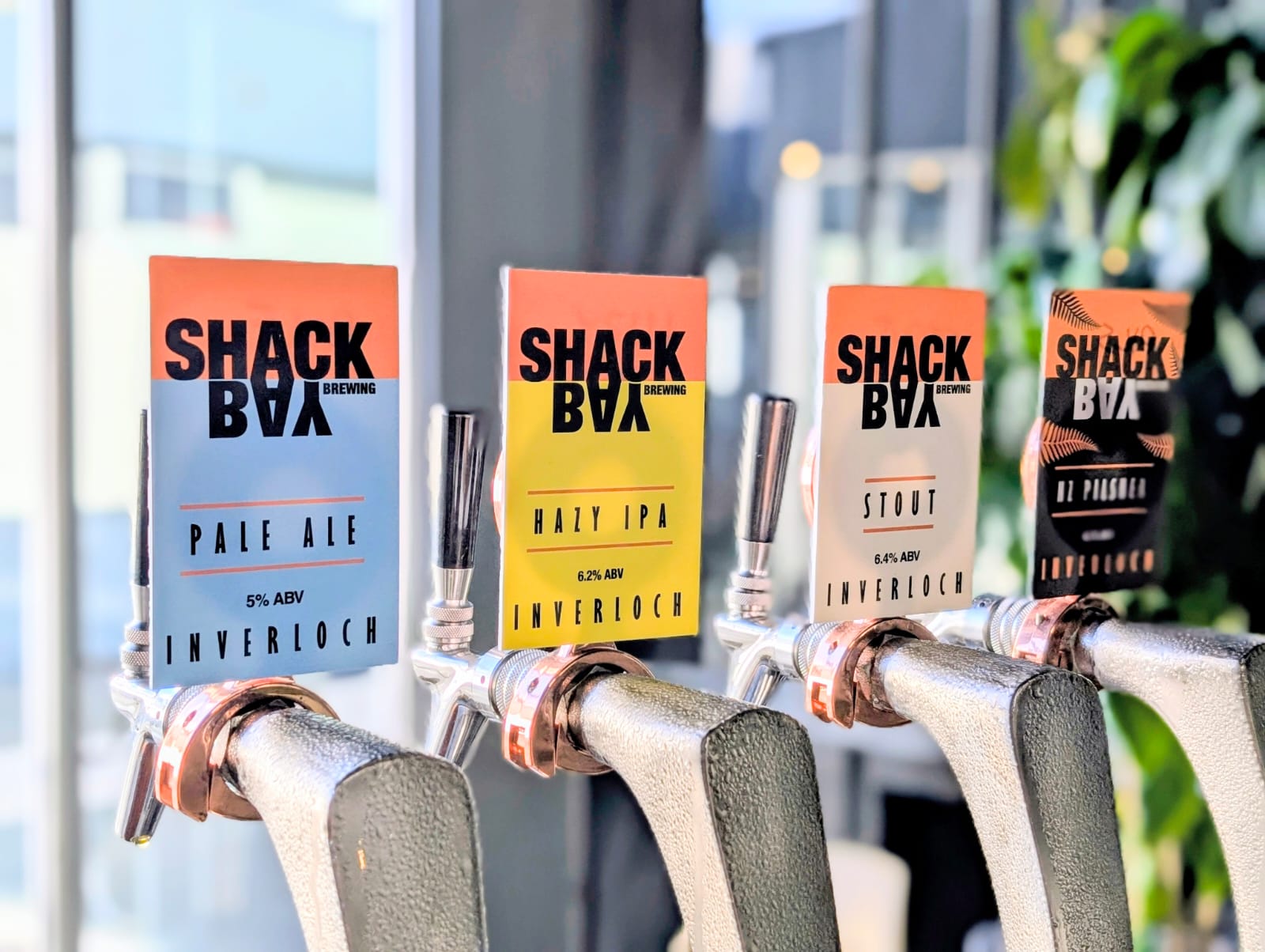 Shack Bay brewing beer taps with colorful decals in an outdoor setting.